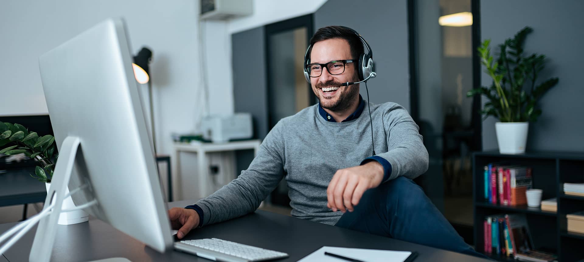 The Best Guide to Rock Your Next Video Assessment Interview | Elevatus A male recruiter wearing headsets and watching a video assessment on his laptop.